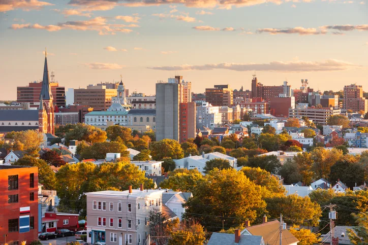 Portland, Maine neighborhood rooftops and church spire at golden hour