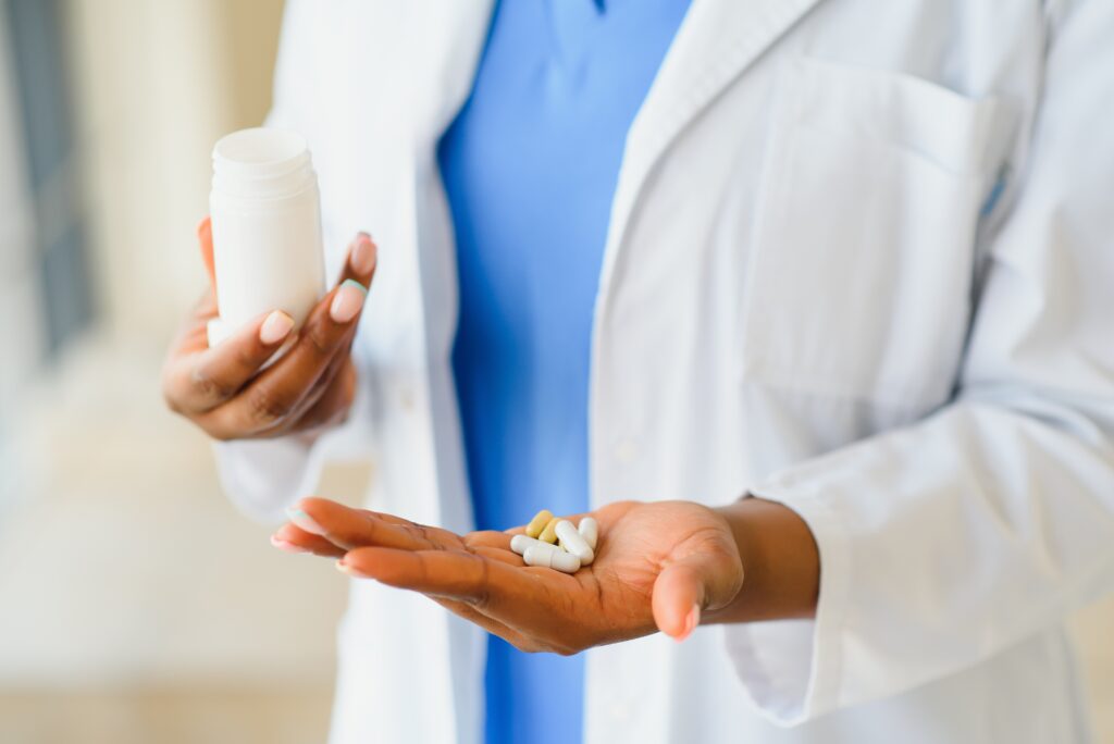 Close-up of an Afro-American doctor showing pills and glass of water